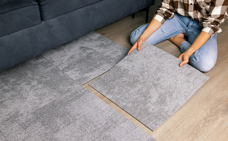 woman installing carpet tile flooring